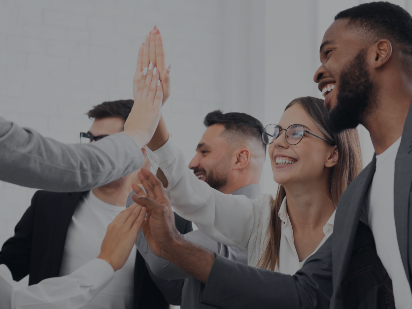 Diverses Team gibt sich einen Highfive bei der Arbeit